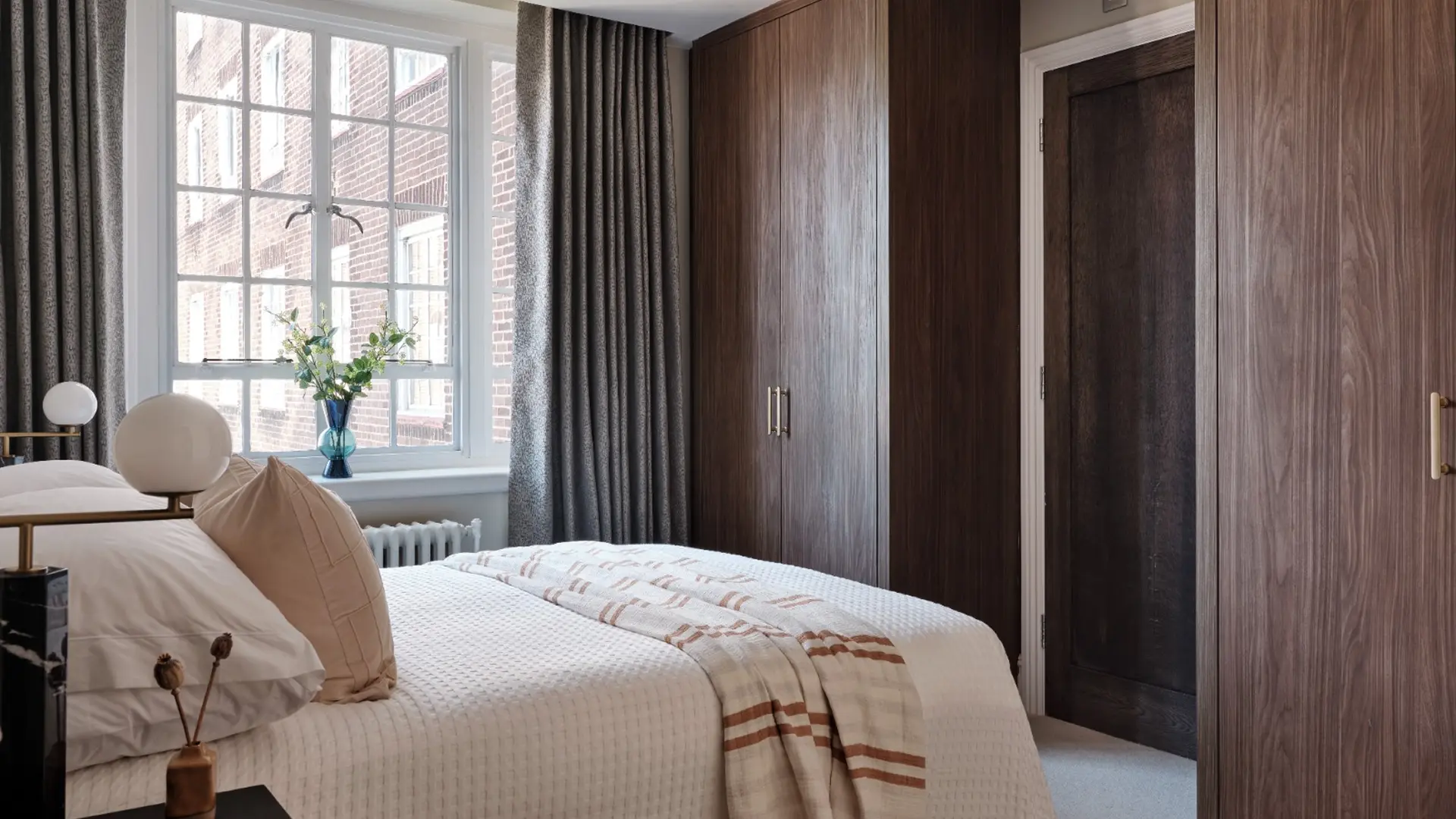 Refined bedroom with dark wood wardrobes and neutral linens